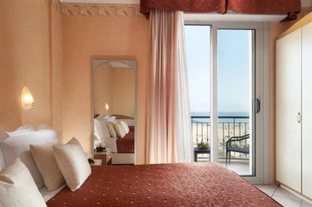 une chambre avec un lit et une vue sur l'océan dans l'établissement Hotel Ambra, à Rimini