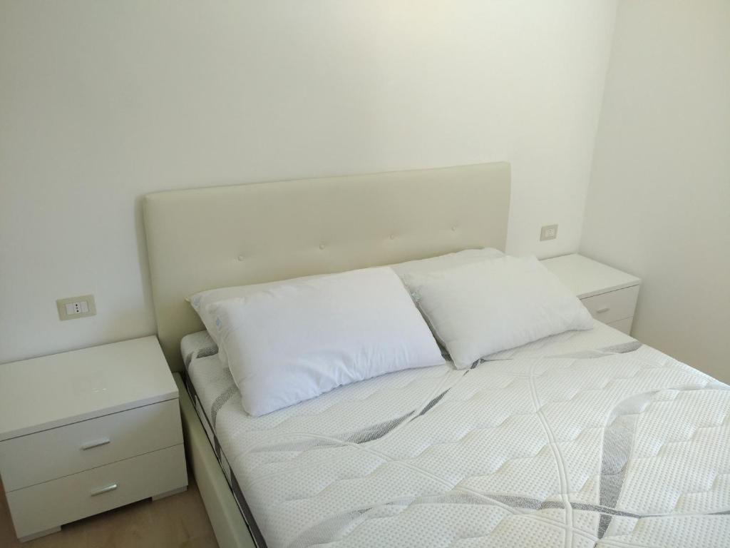 - un lit blanc avec 2 oreillers blancs dans l'établissement Villa Greco, à Rossano