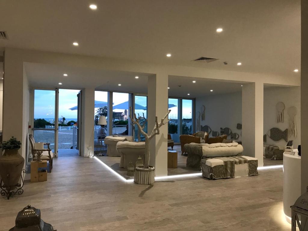 un salon avec des canapés, des chaises et des fenêtres dans l'établissement Stellamare, à Caorle