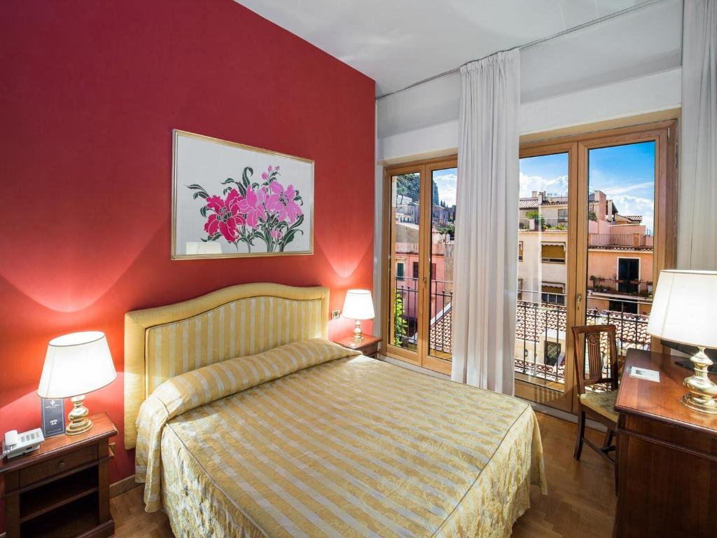 une chambre d'hôtel avec un lit et un balcon dans l'établissement Hotel Isabella, à Taormine