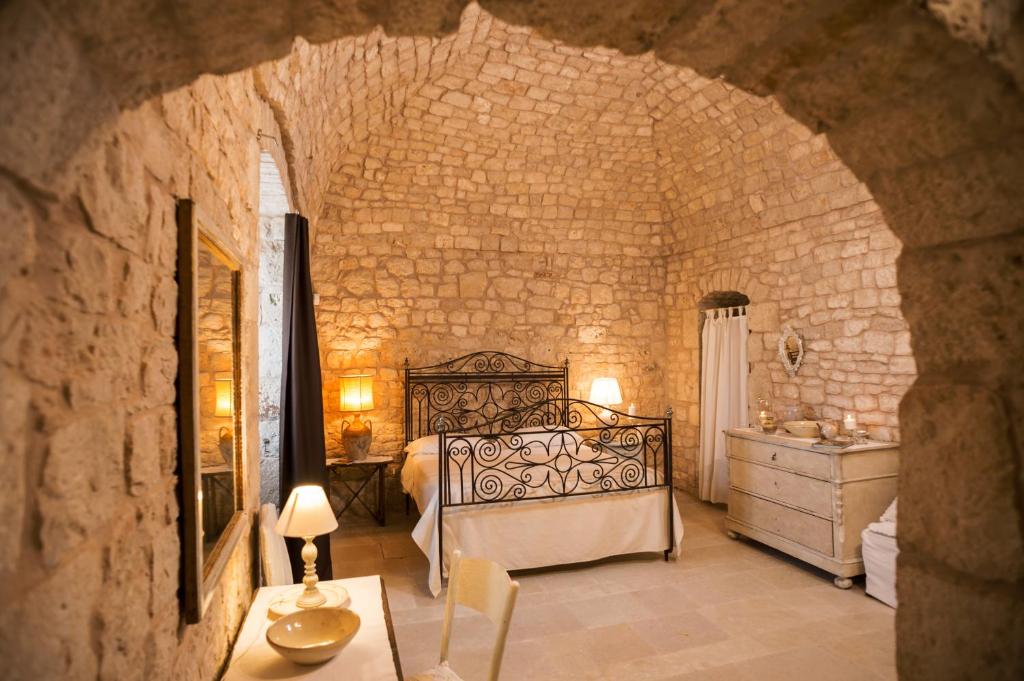 une chambre avec un lit dans un mur de pierre dans l'établissement Masseria Le Cerase, à Conversano