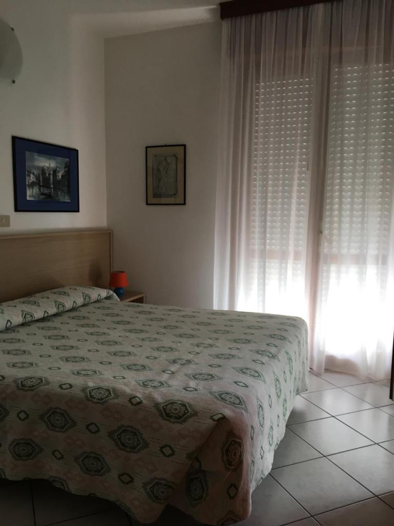 une chambre avec un lit et une fenêtre avec des rideaux dans l'établissement Residence Moresco, à Lido di Jesolo