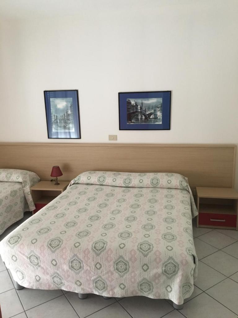 une chambre avec un lit et deux tableaux au mur dans l'établissement Residence Moresco, à Lido di Jesolo