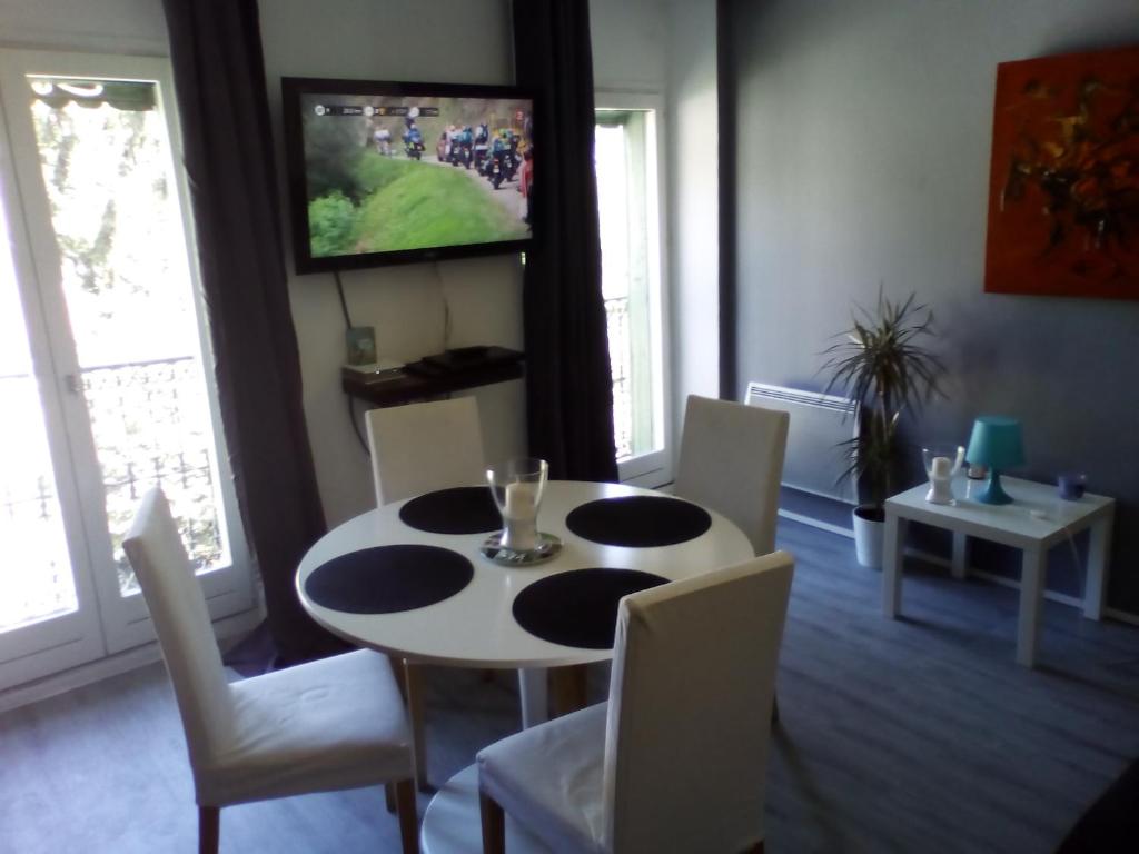 une salle à manger avec une table et des chaises et une télévision dans l'établissement Appartement Résidence les Acacias, à Ax-les-Thermes