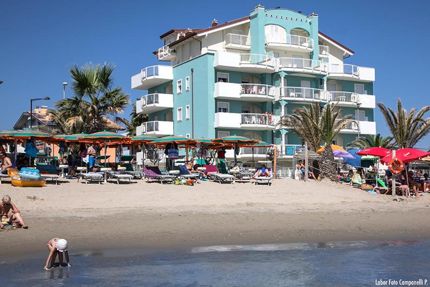 un bâtiment sur la plage avec des gens dans l'eau dans l'établissement Residence Acquasuite, à Martinsicuro