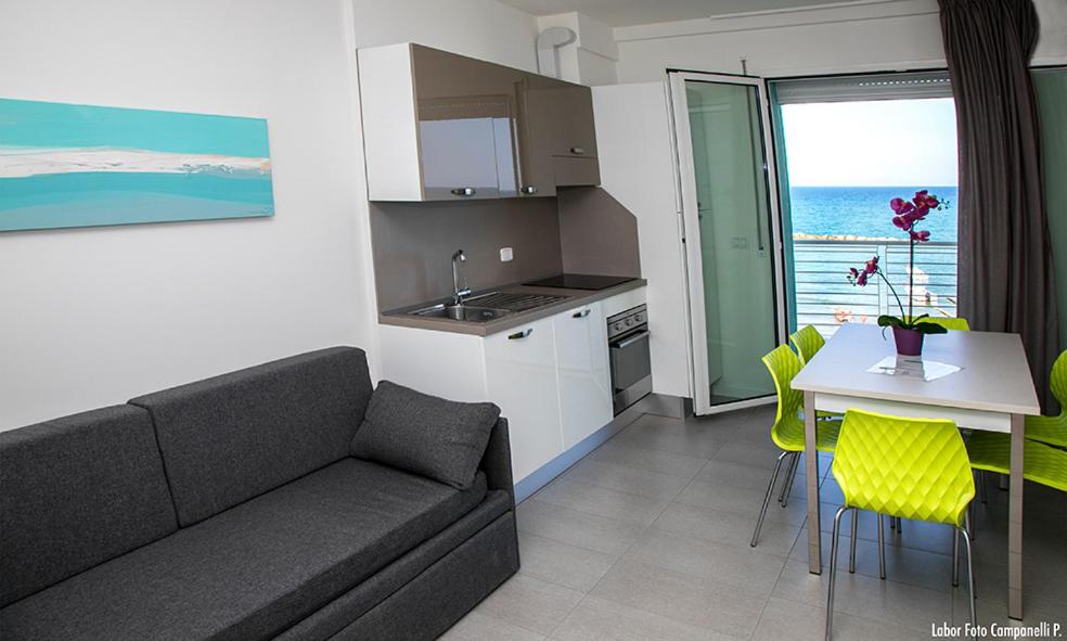 un salon avec un canapé et une table et une cuisine dans l'établissement Residence Acquasuite, à Martinsicuro