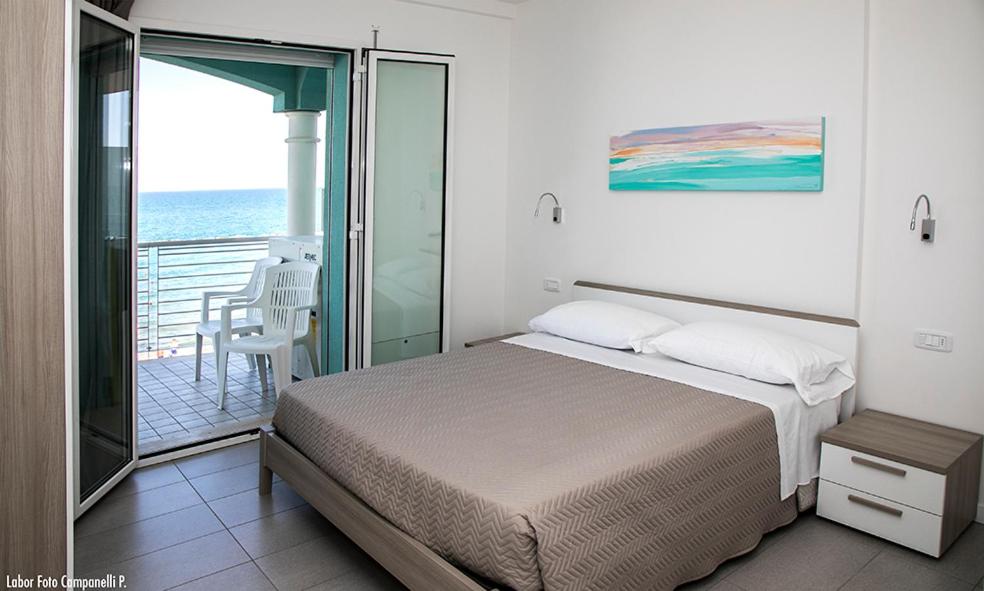 une chambre avec un lit et un balcon avec l'océan dans l'établissement Residence Acquasuite, à Martinsicuro