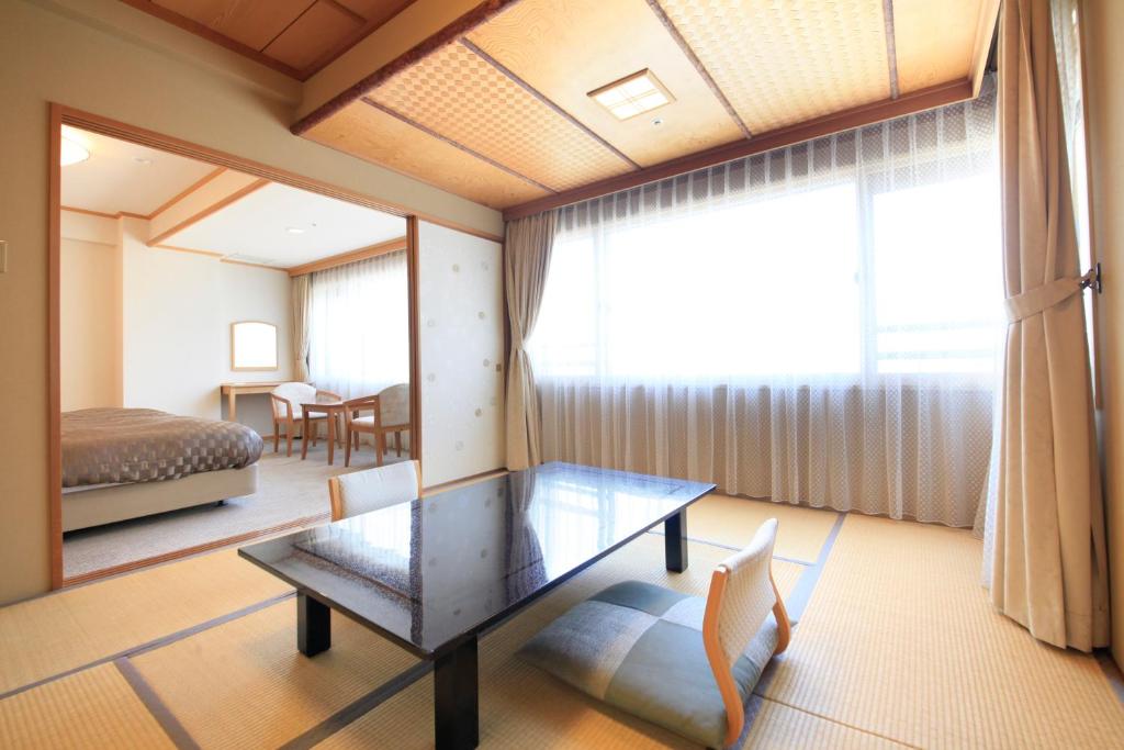 Cette chambre comprend une table, un lit et une fenêtre. dans l'établissement Heiseikan Shiosaitei, à Hakodate 33 autres photos