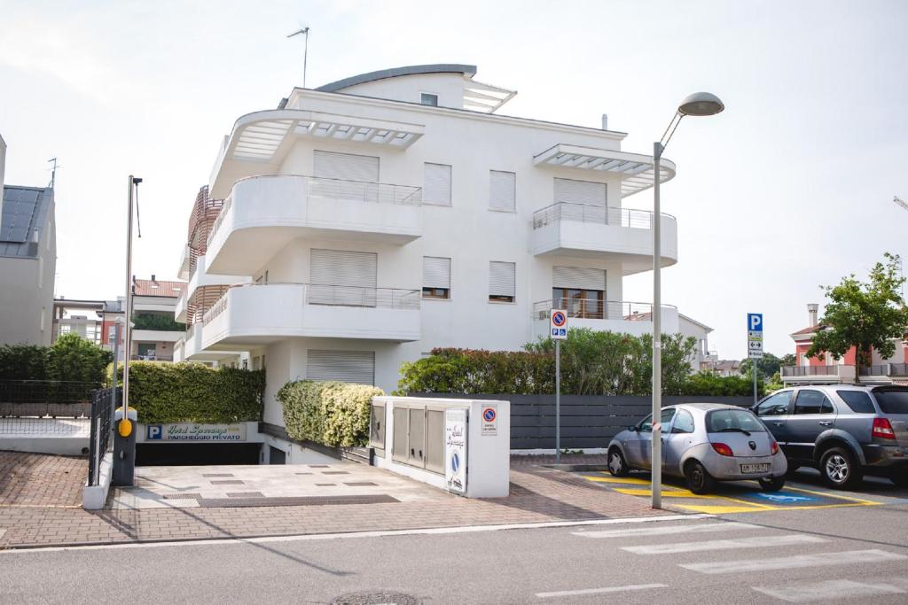 un bâtiment blanc avec des voitures garées devant dans l'établissement Residence Speranza, à Lido di Jesolo