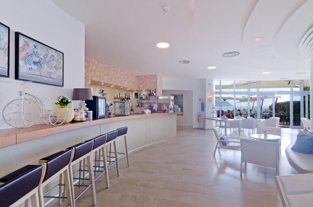 un restaurant avec un bar avec des chaises et une table dans l'établissement Hotel Riviera dei Fiori, à San Lorenzo al Mare