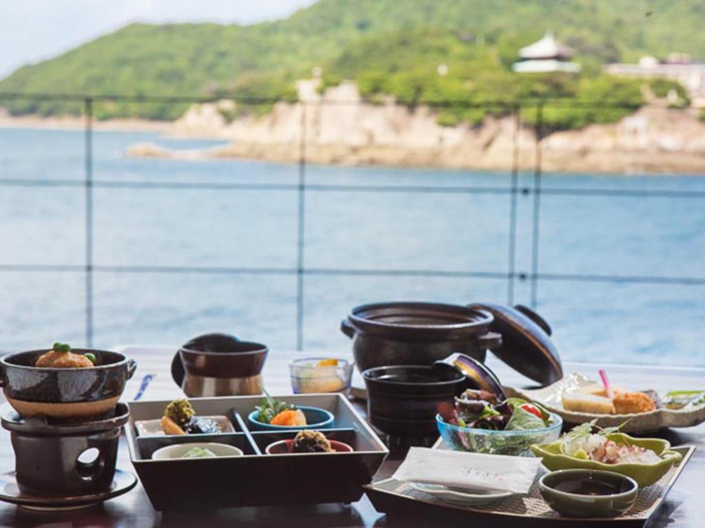 une table avec des plaques alimentaires sur une table près de l'eau dans l'établissement Migiwatei Ochi Kochi, à Fukuyama