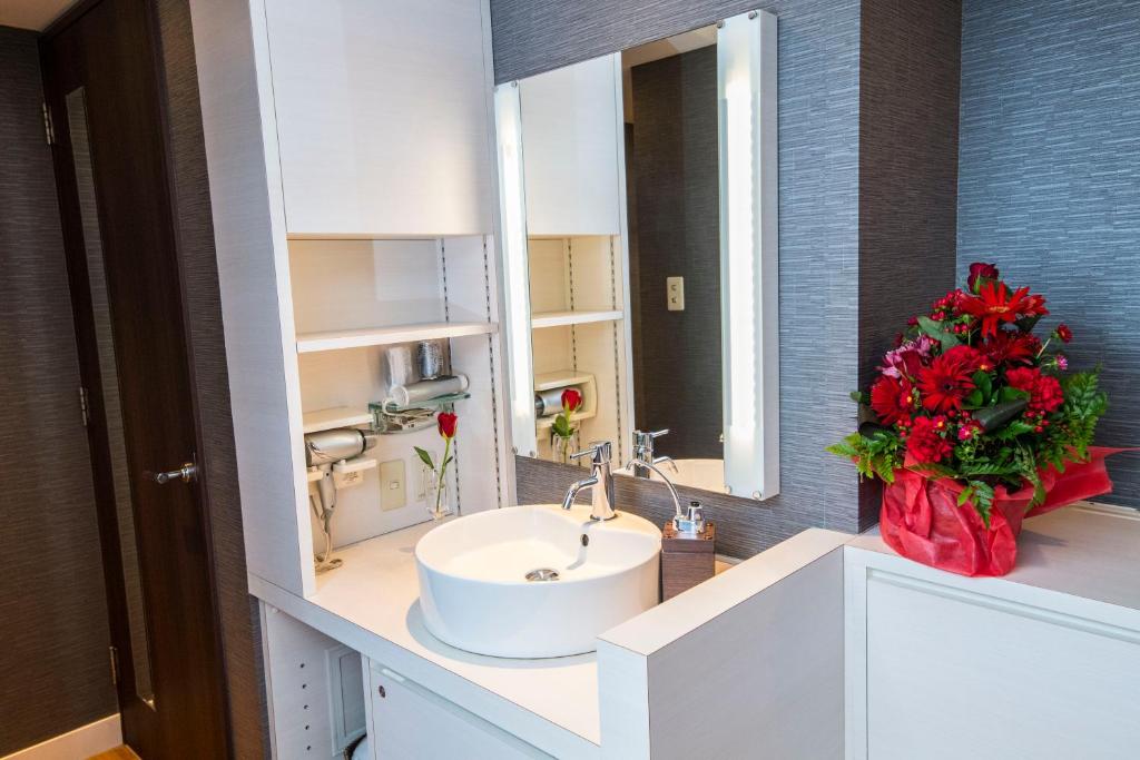 une salle de bain avec un lavabo et un vase de fleurs rouges dans l'établissement HOTEL ATLAS Shinkabukicho (Adult Only), à Tokyo 62 autres photos