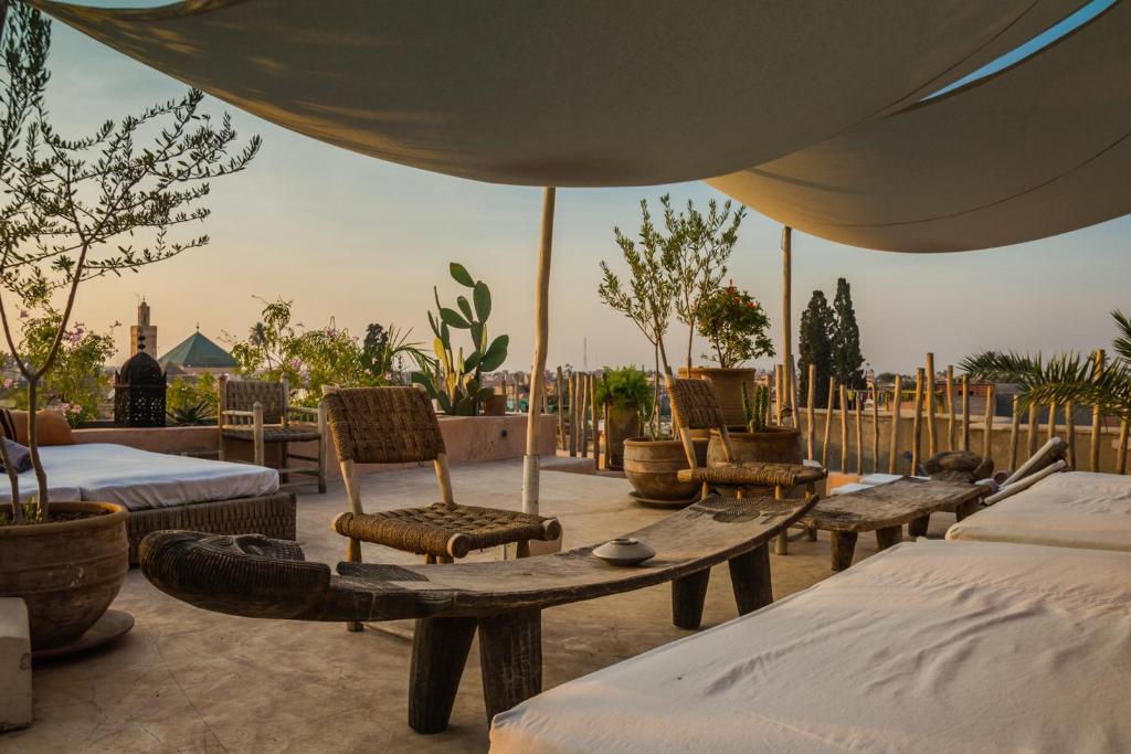 - une terrasse avec des lits, des chaises et un parasol dans l'établissement Riad 144, à Marrakech