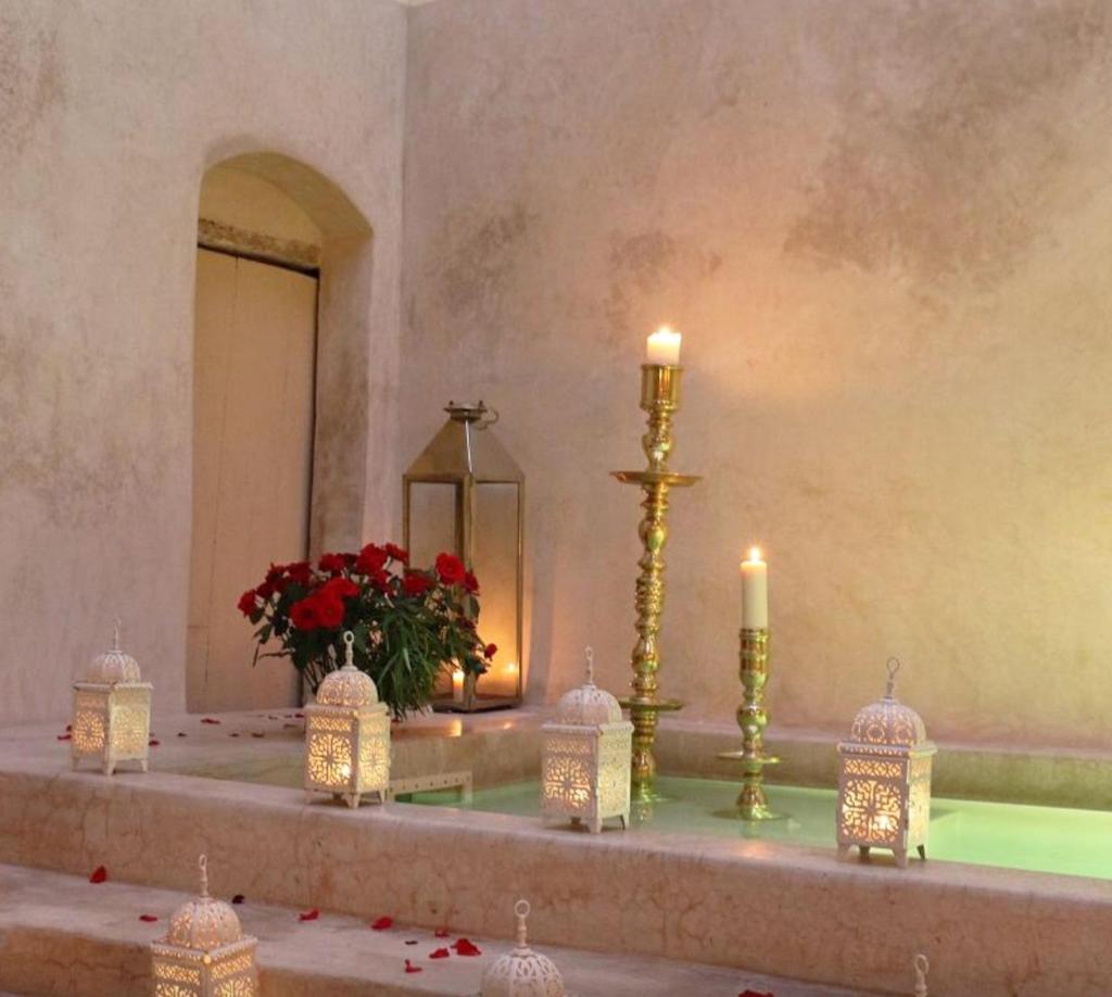 un autel avec des bougies et un vase avec des fleurs rouges dans l'établissement Riad 144, à Marrakech