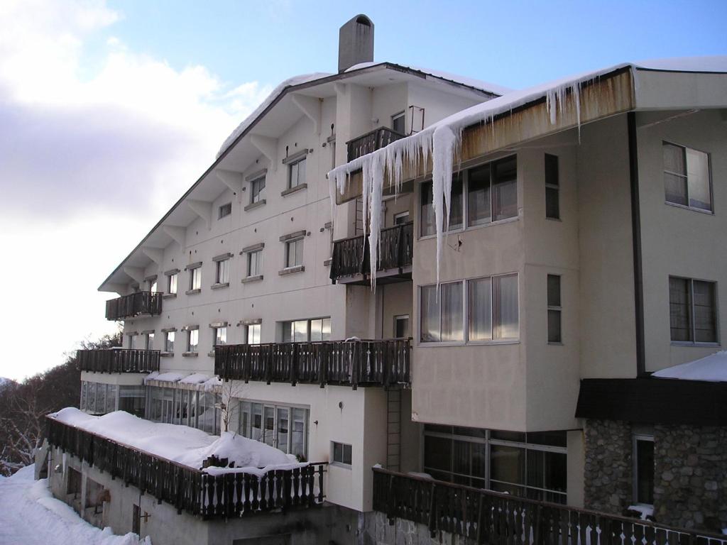 un grand bâtiment blanc recouvert de neige dans l'établissement Hotel Takimoto, à Yamanouchi