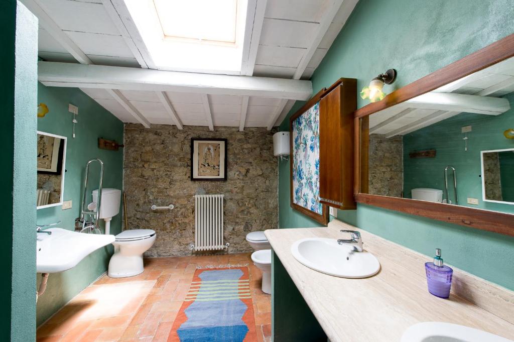 une salle de bain avec des murs verts et un lavabo et des toilettes dans l'établissement Il Granaio, à San Venanzo