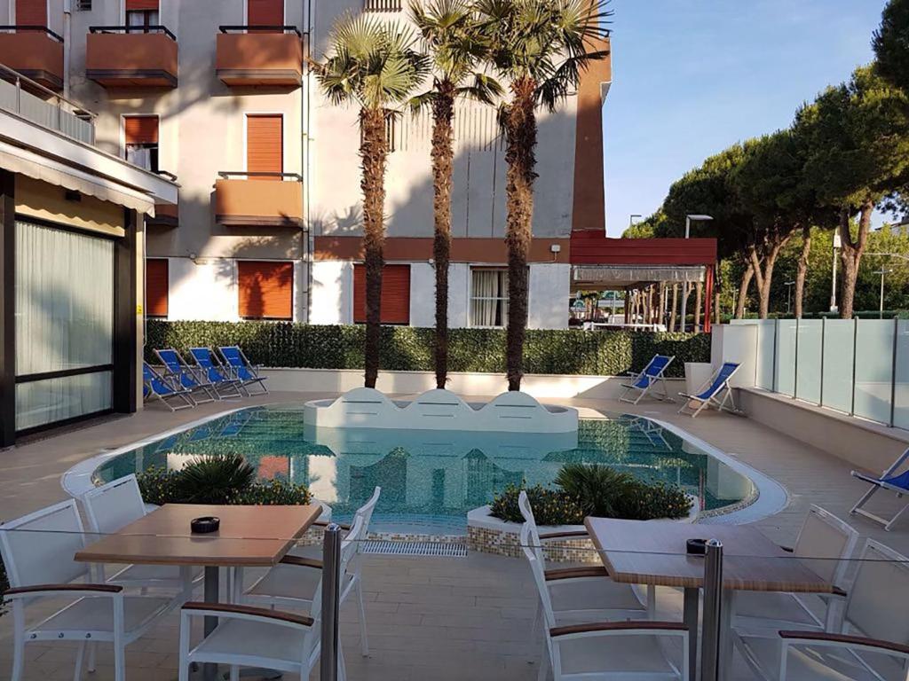 un patio avec tables et chaises et une piscine dans l'établissement Hotel Maré - Valentini Family Village, à Bellaria-Igea Marina