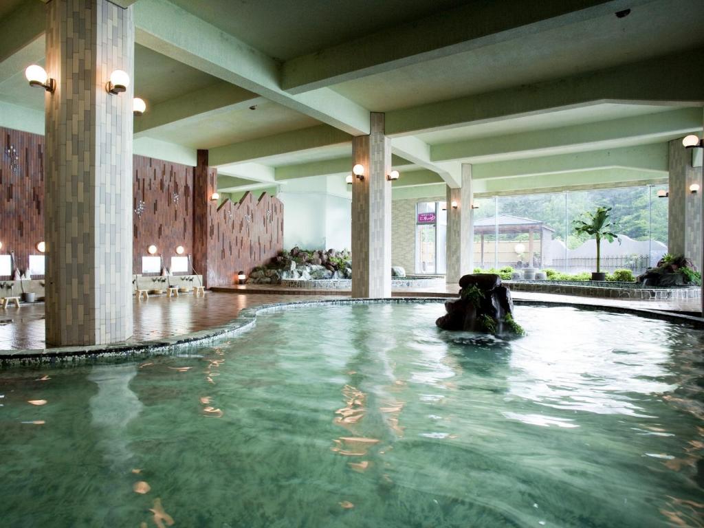 une personne se baignant dans une piscine dans un bâtiment dans l'établissement Hotel Abashirikoso, à Abashiri