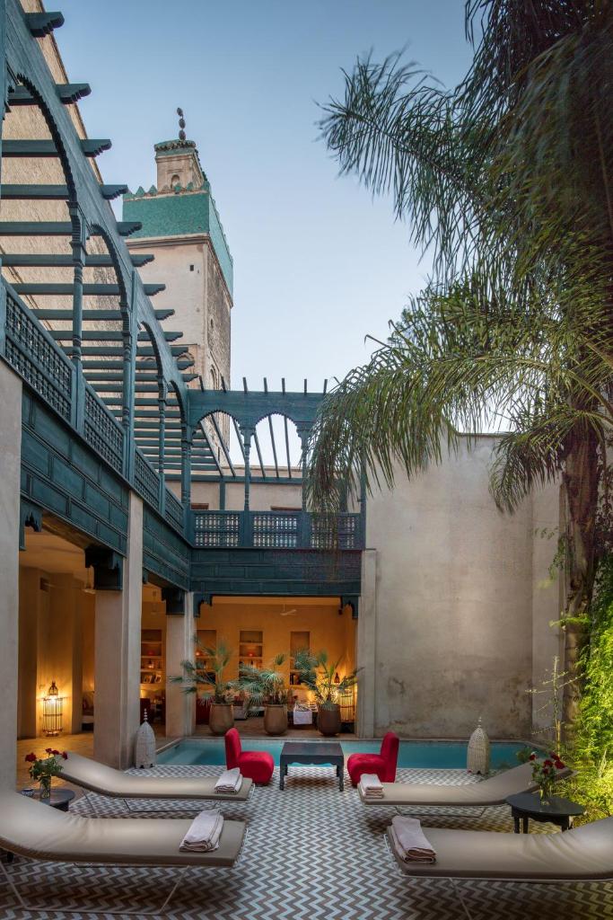 un patio extérieur avec des chaises longues et une table dans l'établissement Hotel & Spa Dar Bensouda, à Fès