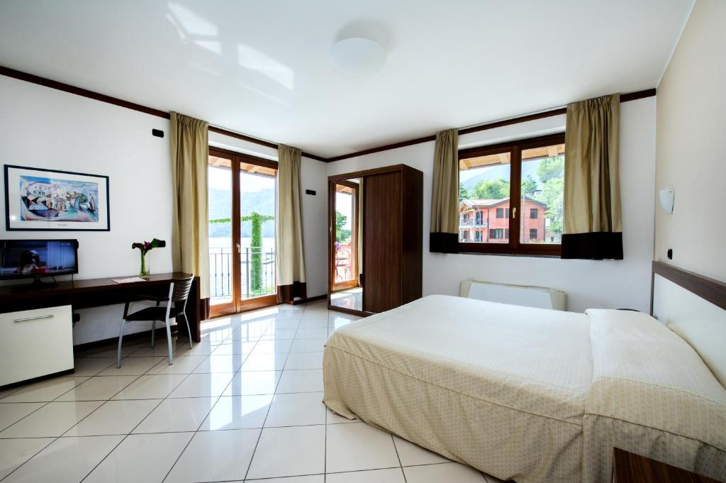 une chambre avec un lit, un bureau et des fenêtres dans l'établissement Hotel & Residence La Sibilla Cusiana, à Pettenasco