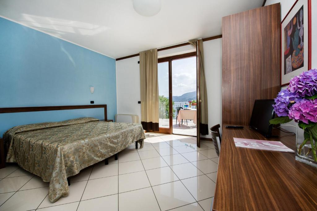 une chambre avec un lit et une table avec un vase de fleurs dans l'établissement Hotel & Residence La Sibilla Cusiana, à Pettenasco