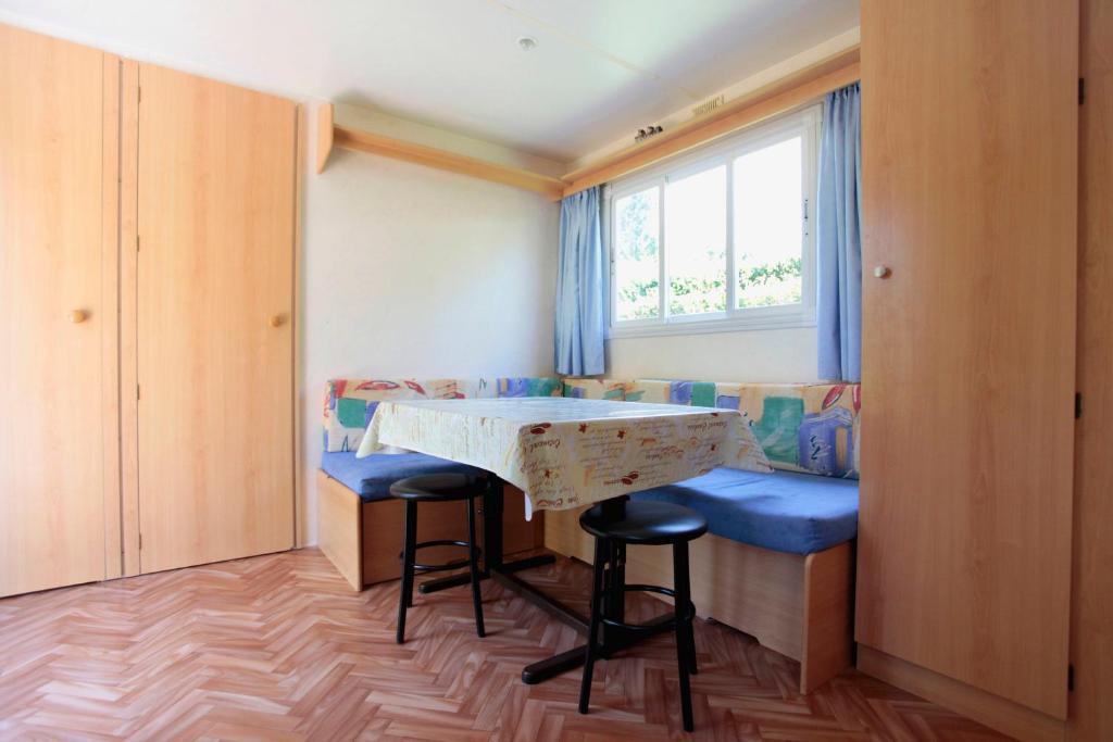 une petite chambre avec une table, des tabourets et une fenêtre dans l'établissement Camping Du Pont De St Gal, à Saint-Gal-sur-Sioule