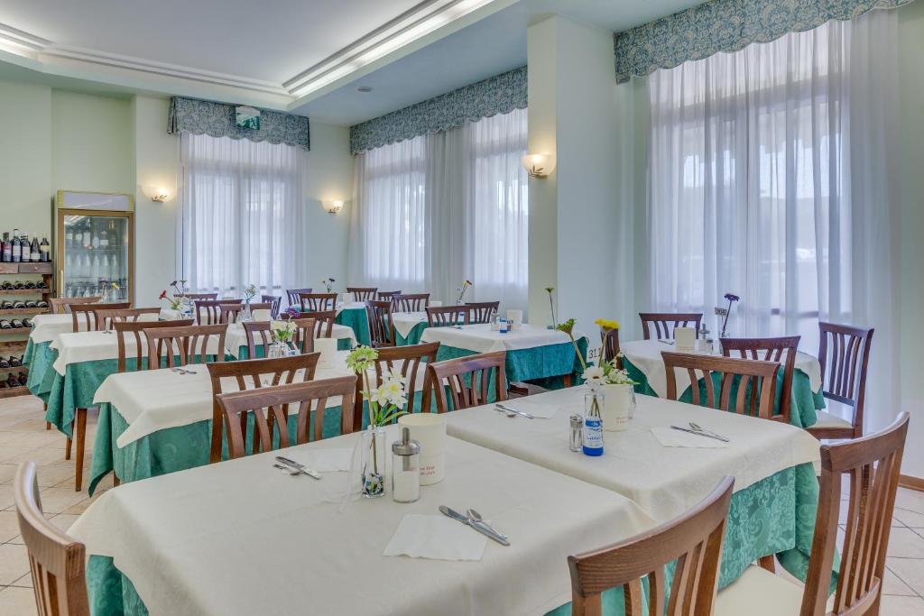 une salle à manger avec des tables et des chaises blanches dans l'établissement Hotel Austria, à Caorle