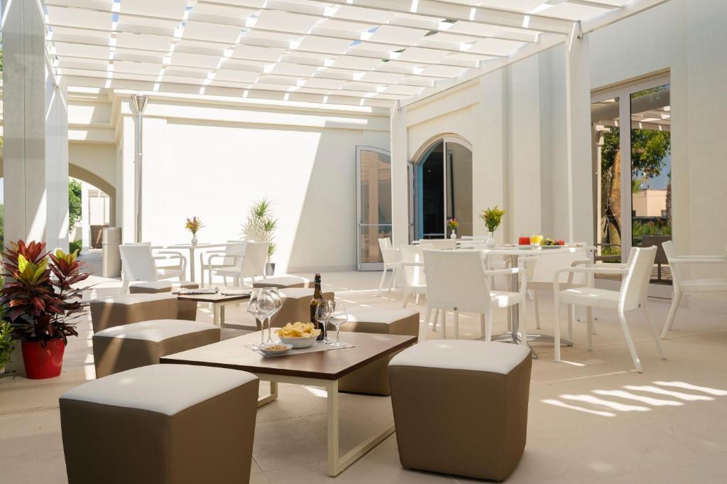 un restaurant avec des tables et des chaises blanches dans l'établissement Le Dune Suite Hotel, à Porto Cesareo
