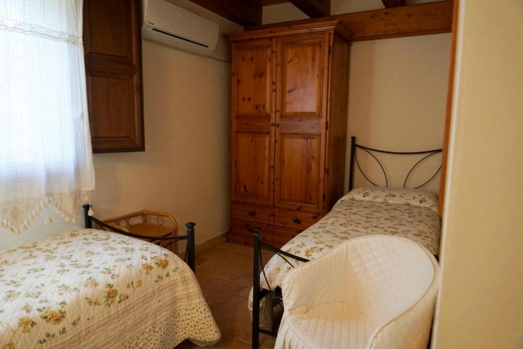 une chambre avec deux lits et une armoire en bois dans l'établissement Taormina Villa Ibiscus Alcantara, à Gaggi