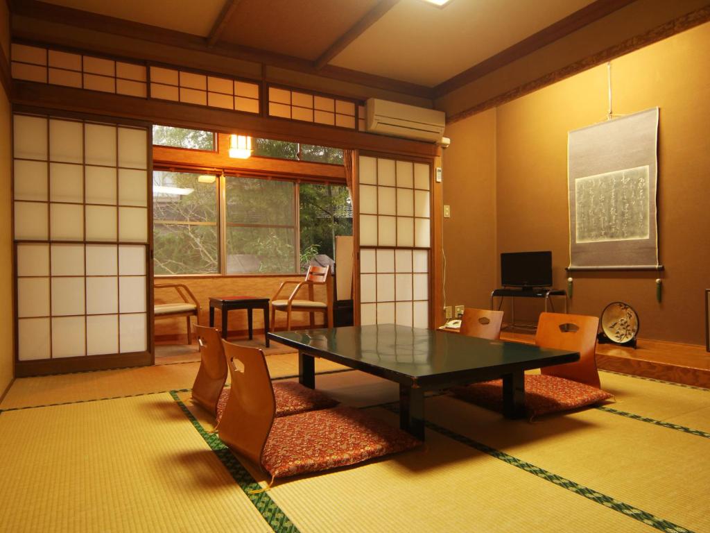 une pièce avec une table, des chaises et une fenêtre dans l'établissement Suehirokan, à Tagami