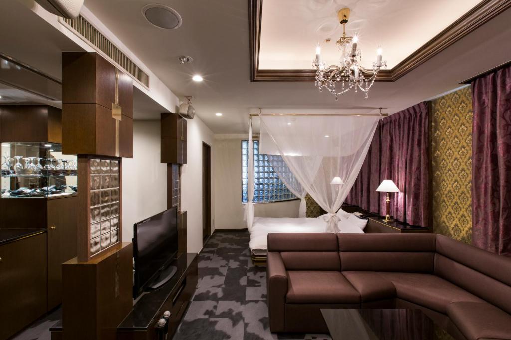 une chambre d'hôtel avec un canapé et un lit dans l'établissement Hotel Rio (Adult Only), à Sapporo