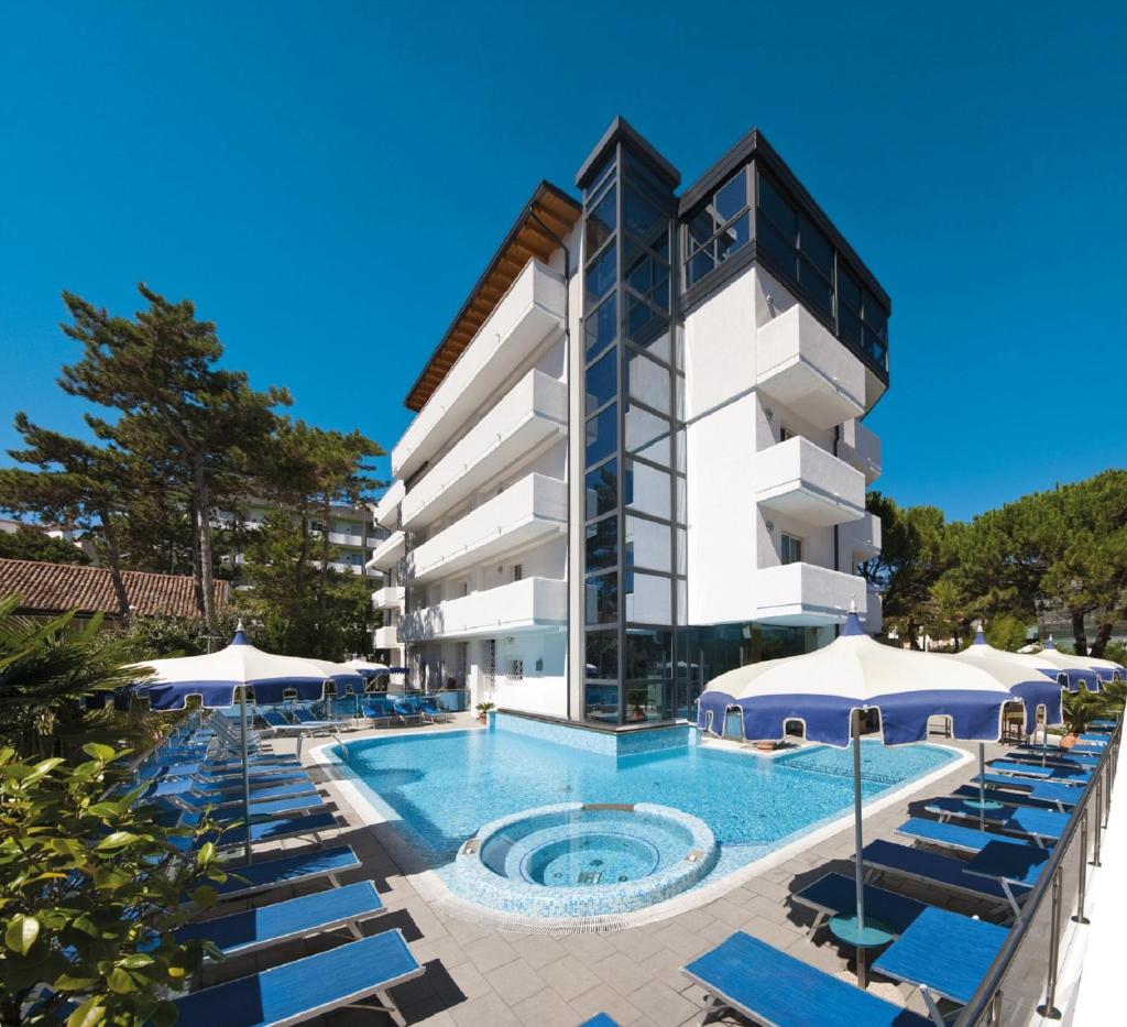 un hôtel avec piscine et chaises longues dans l'établissement Hotel Bellevue, à Lignano Sabbiadoro