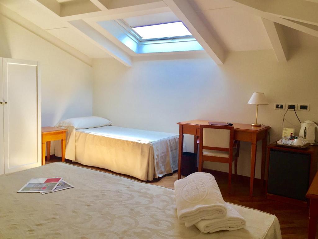 une chambre avec deux lits, un bureau et une fenêtre dans l'établissement Hotel Claila, à Francavilla al Mare