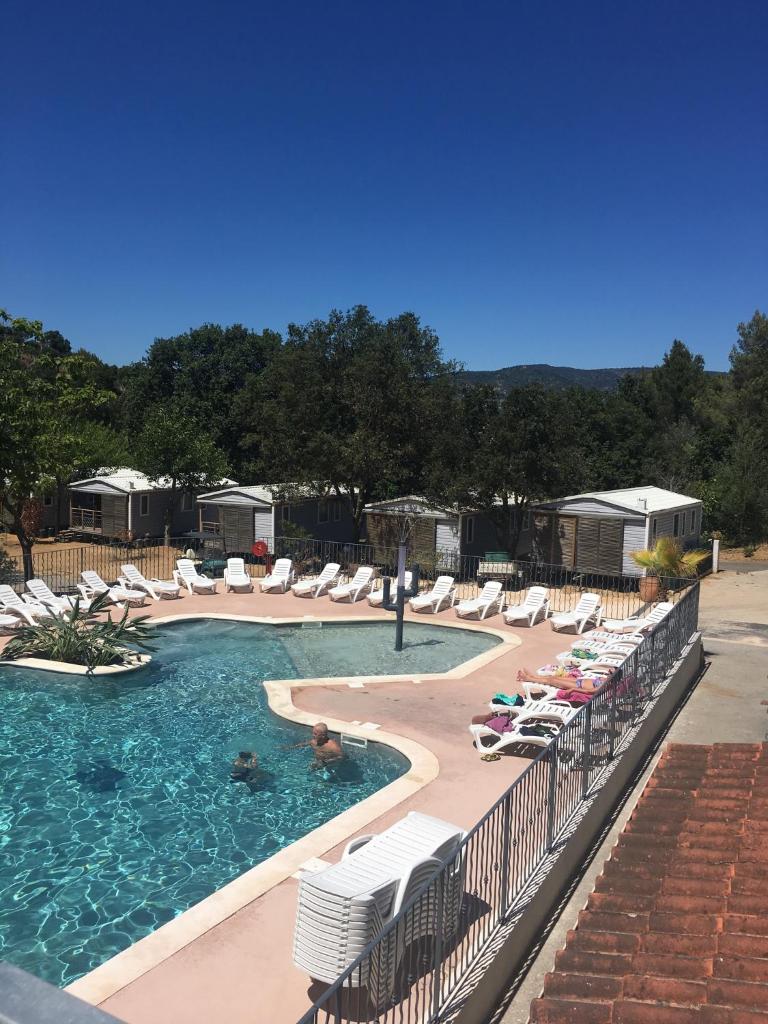 une grande piscine avec des chaises et des chaises de jardin dans l'établissement Camping Lou Cabasson, à Bormes-les-Mimosas