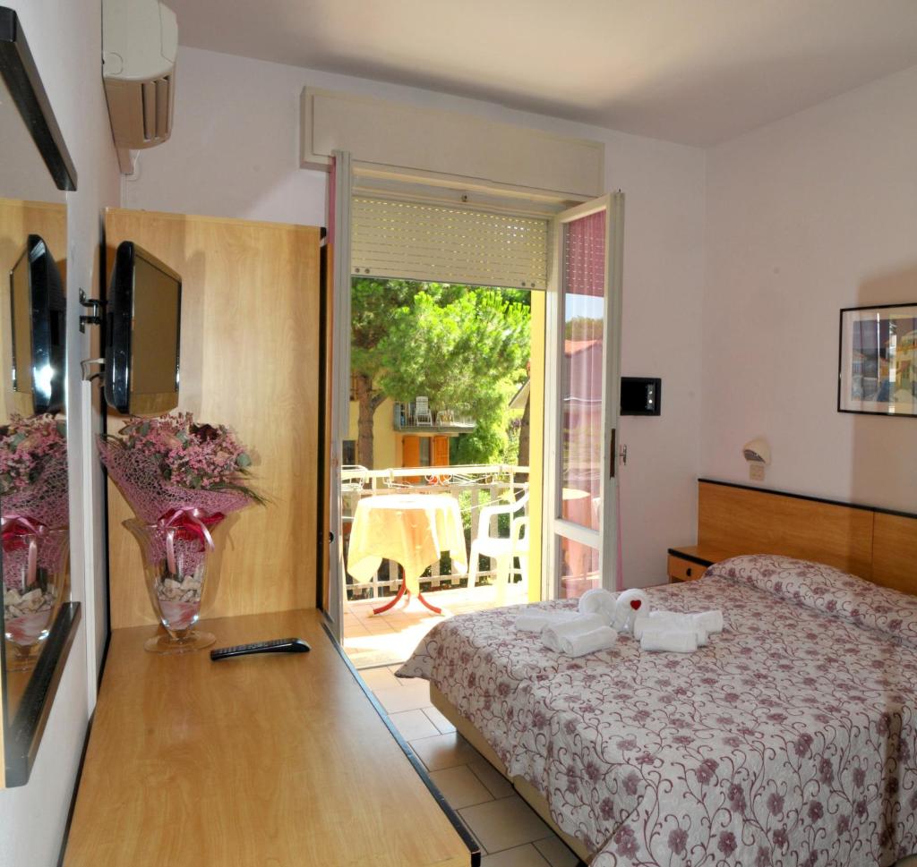 - une chambre avec un lit et une porte donnant sur une terrasse dans l'établissement Hotel Levante, à Cervia