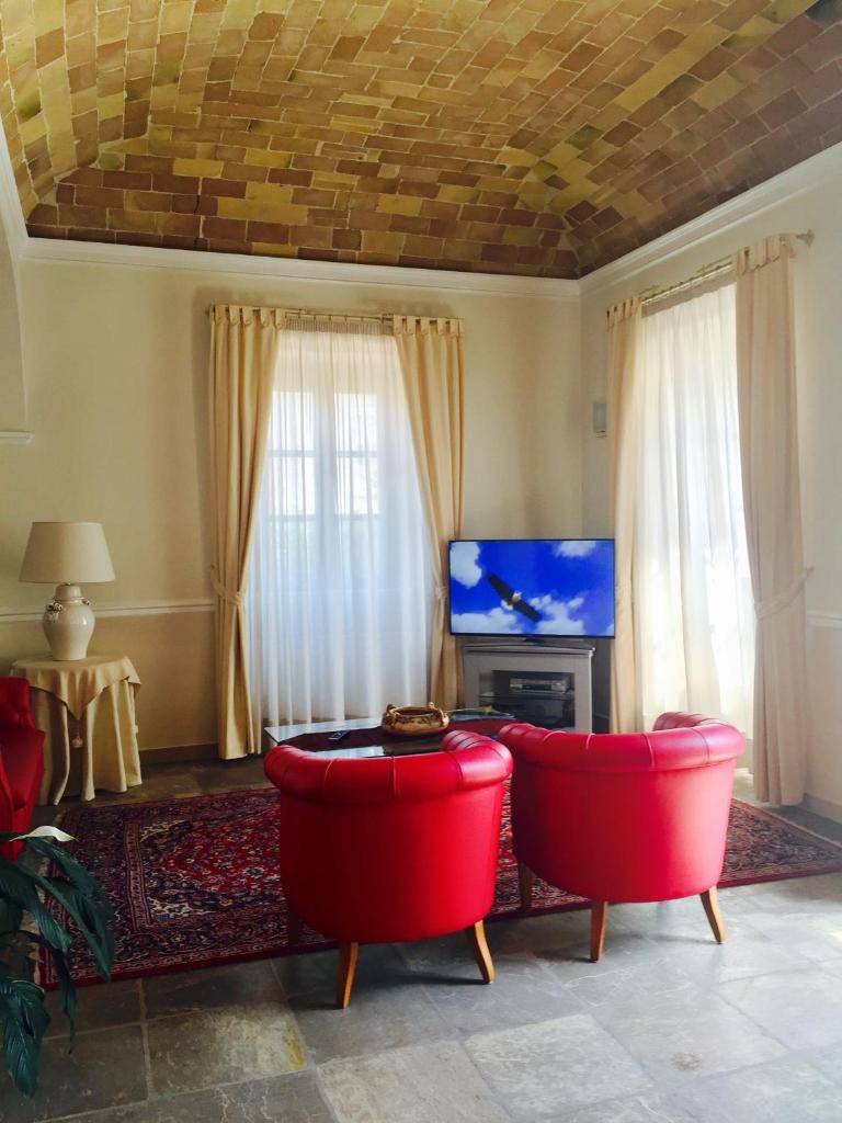 un salon avec deux chaises rouges et une télévision dans l'établissement Hotel Claila, à Francavilla al Mare