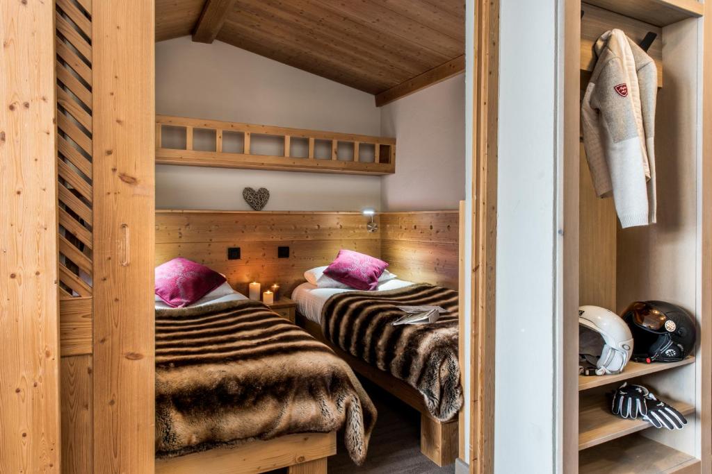 deux lits dans une chambre aux murs en bois dans l'établissement Village Montana, à Val Thorens