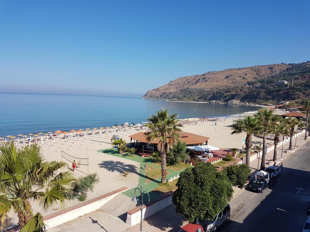 une plage avec beaucoup de parasols et de palmiers dans l'établissement Hotel Nautilus, à Nicotera Marina