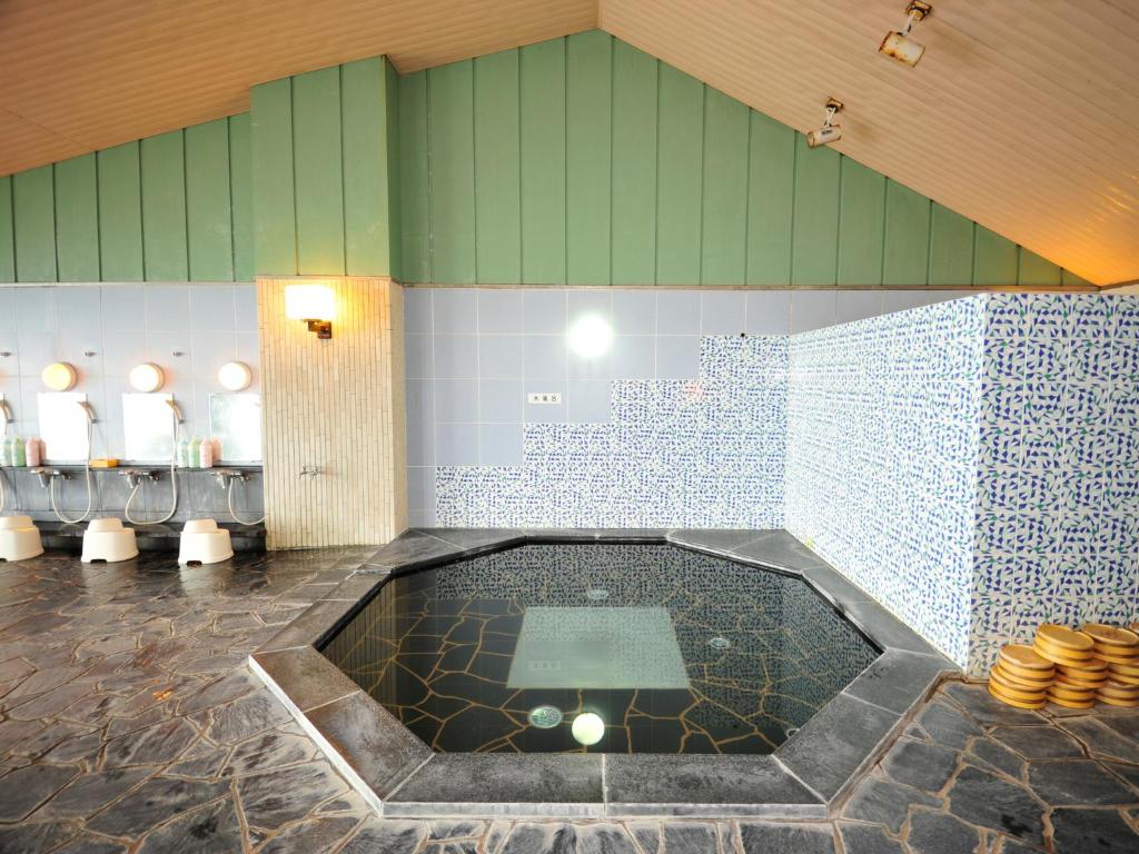 une salle de bain avec une baignoire au milieu d'une pièce dans l'établissement Nisshokan Shinkan Baishokaku, à Nagasaki