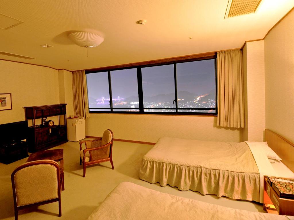 une chambre d'hôtel avec un lit et une grande fenêtre dans l'établissement Nisshokan Shinkan Baishokaku, à Nagasaki