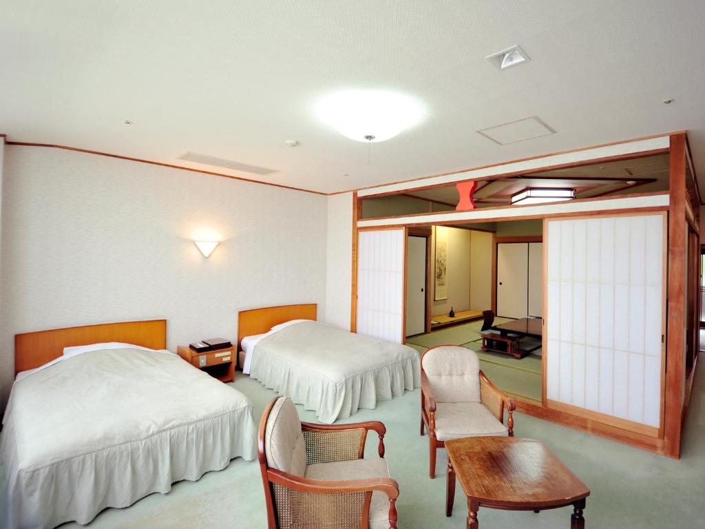 une chambre d'hôtel avec deux lits, une table et des chaises dans l'établissement Nisshokan Shinkan Baishokaku, à Nagasaki 21 autres photos