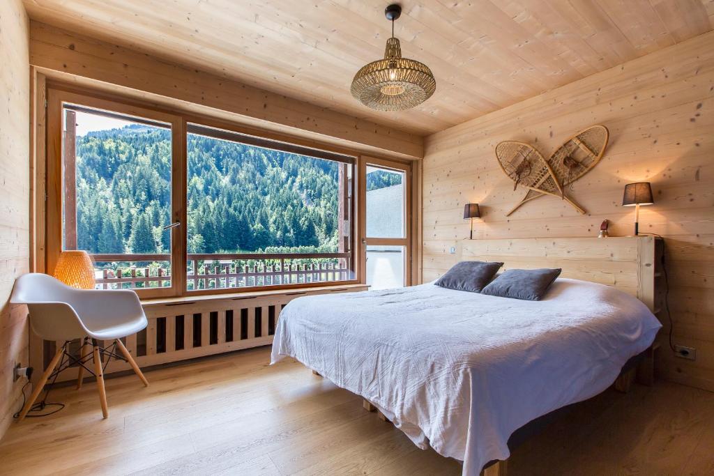 une chambre avec un lit et une grande fenêtre dans l'établissement Appartement Le Danay 10 personnes, au Grand-Bornand