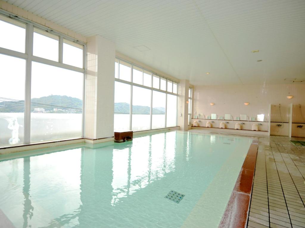 - une grande piscine d'eau bleue dans une chambre avec fenêtres dans l'établissement Nagasaki Nisshokan, à Nagasaki