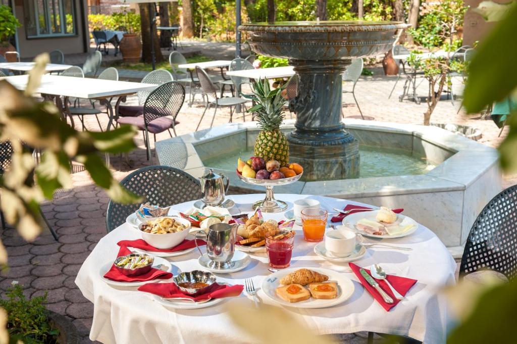 une table avec des assiettes de nourriture et une fontaine dans l'établissement Albergo Battelli Only Adults, à Marina di Pietrasanta 78 autres photos