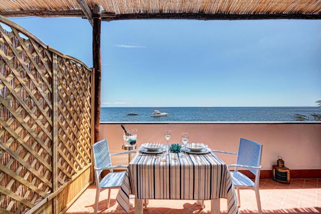 une table et des chaises sur un balcon avec l'océan dans l'établissement Belmare Residence on the beach, à Nerano