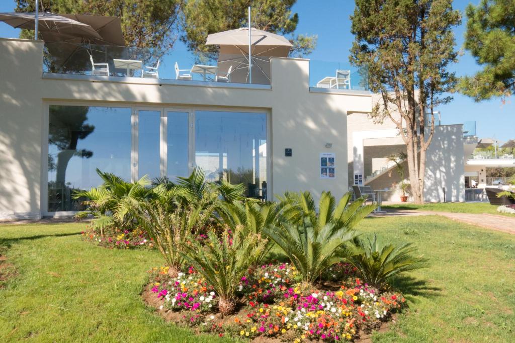 une maison blanche avec des plantes et des fleurs dans une cour dans l'établissement TUI BLUE Tropea, à Santa Domenica