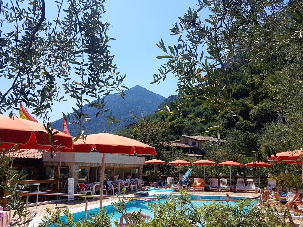 un complexe avec une piscine avec des parasols et une montagne dans l'établissement Residence Miravalle, à Limone sul Garda
