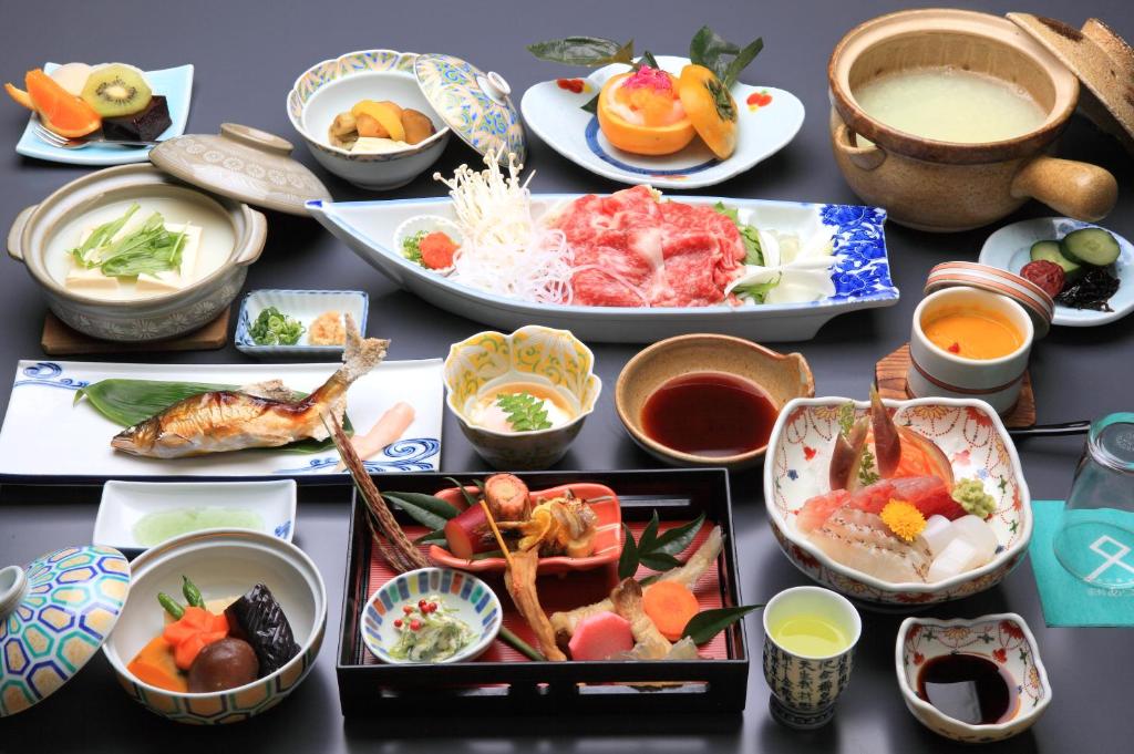 une table avec des assiettes et des bols de nourriture dans l'établissement Ryokan Adumaya, à Hongu