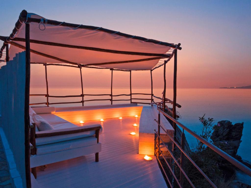 - un lit sur une terrasse avec des lumières sur l'eau dans l'établissement Hotel Kalura, à Cefalù