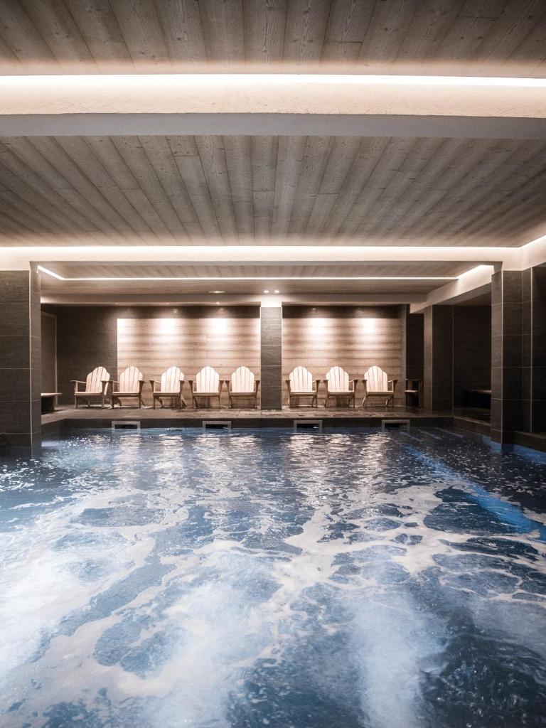 - une piscine d'eau dans une pièce avec des chaises dans l'établissement Le Fitz Roy, a Beaumier hotel, à Val Thorens